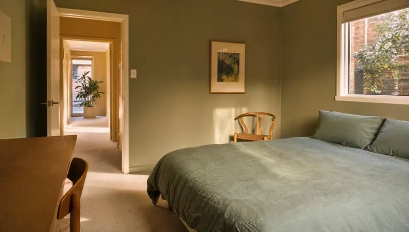 Bright spare bedroom with a made bed and an open door, ready for a housemate